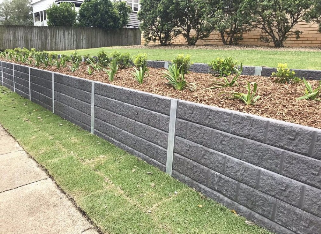 Professional concrete retaining wall with textured blocks and landscaping