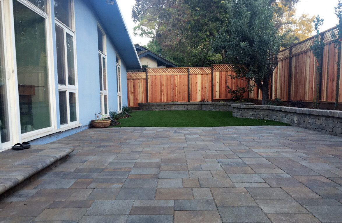 Custom concrete patio with decorative pavers in residential backyard